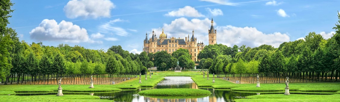 Schloss von Schwerin am See bei Sonnenschein mit Verlauf in Bild mit Frühstücksteller und Kaffee.