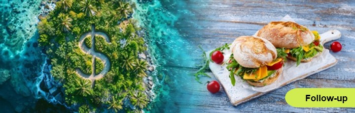 Kleine grüne Insel im Meer mit Dollarzeichen als Weg geht in Bild von belegten Brötchen auf einem Tisch über.