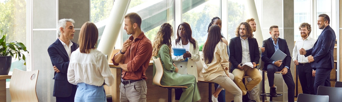 Nah-Blick auf einen Konferenztisch im Sonnenschein, auf dem ein Laptop, Papiere und Kaffeetassen stehen.