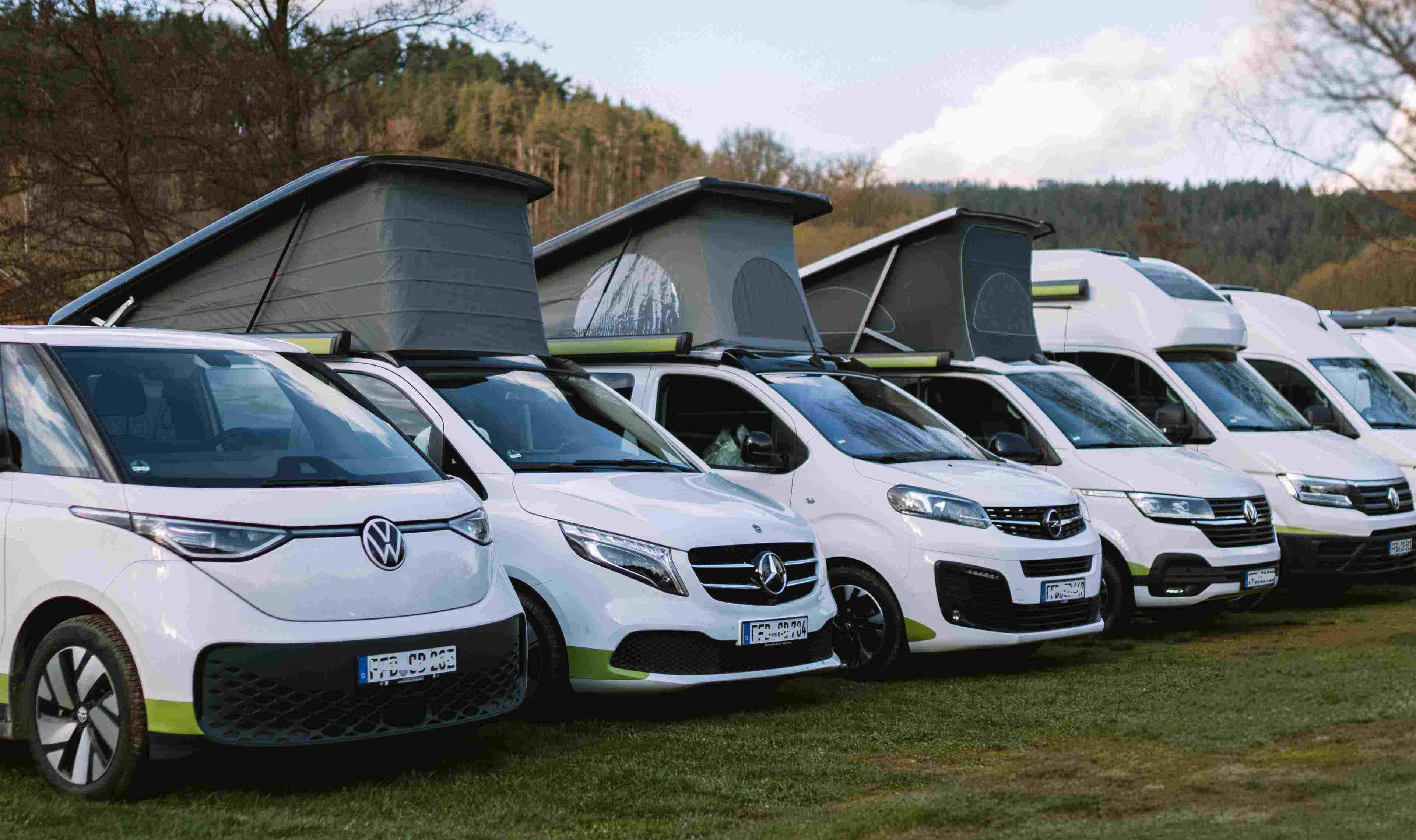 Foto: Die Campervan-Flotte des Camper-Vermieters Off steht aufgereiht auf einer grünen Wiese.