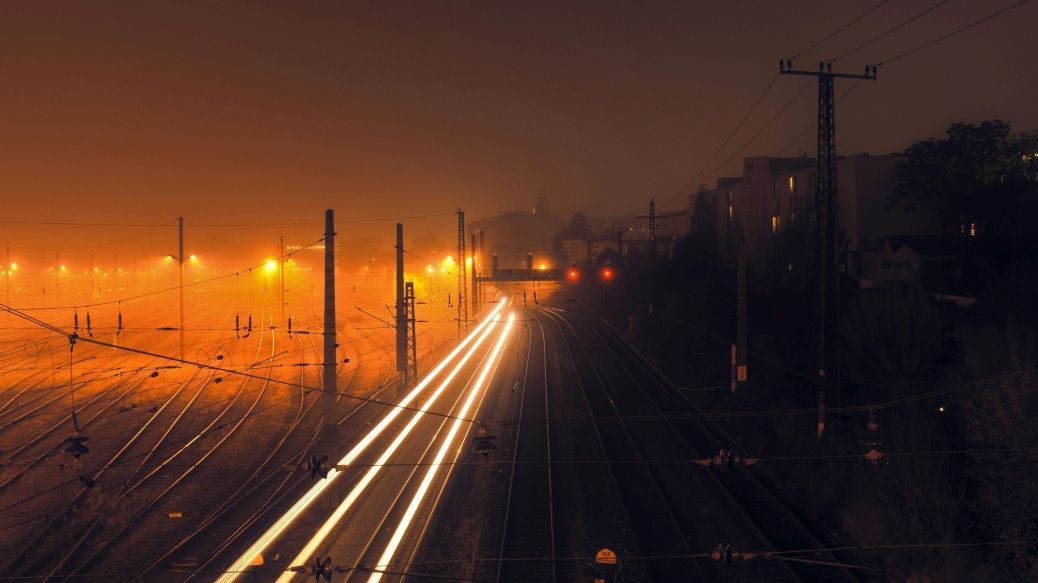  Image: A nocturnal railroad layout with glowing light traces of a moving train