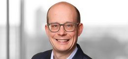 Foto: Andreas Roehr lächelt freundlich in die Kamera. Er trägt einen dunkelblauen Anzug und eine weißes Hemd.