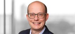Foto: Andreas Roehr lächelt freundlich in die Kamera. Er trägt einen dunkelblauen Anzug und eine weißes Hemd.