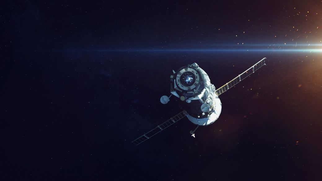 Foto: Ein Satellit im schwarzen Weltall. Von der rechten Seite fällt Licht in die Kamera und erzeugt einen Blendeffekt.
