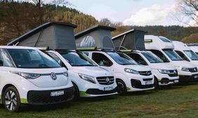 Foto: Die Campervan-Flotte des Camper-Vermieters Off steht aufgereiht auf einer grünen Wiese.