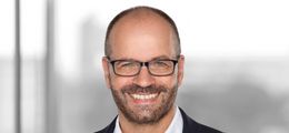 Foto: Porträt von Cornelius Obier. Er lächelt in die Kamera.
