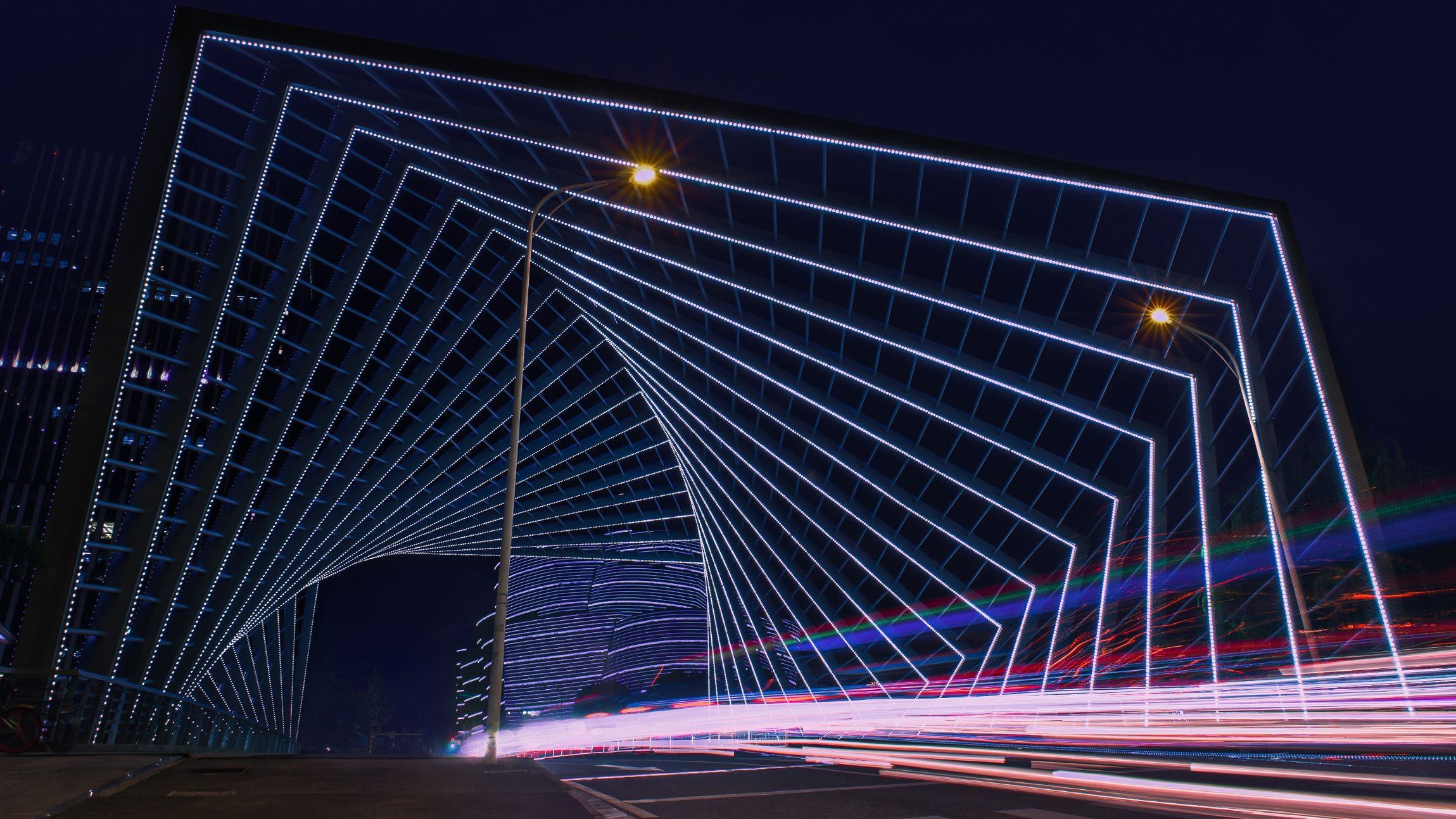 Bild: Eine futuristisch beleuchtete Straßenüberführung bei Nacht mit geometrisch angeordneten LED-Lichtlinien